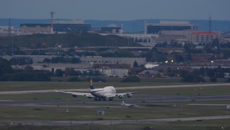 Airplane-ascending-gracefully-during-dusk-at-Toronto-airport,-lights-aglow,-cityscape-in-backdrop,-wide-shot