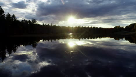 Slow-moving-drone-shot-of-a-sunset-over-a-calm-mirror-reflective-lake