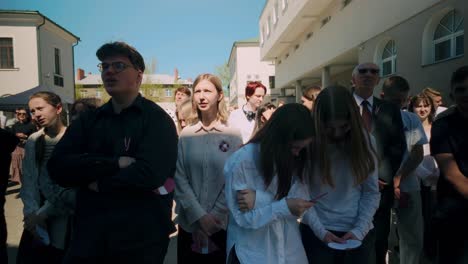 Chicos,-Chicas-Y-Niños-De-Secundaria-Vestidos-De-Blanco-Y-Negro-Parados-En-El-Patio-Escuchando-Y-Cantando