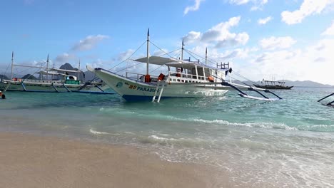 Ein-Pumpboot-Schwimmt-Auf-Dem-Klaren,-Türkisfarbenen-Wasser-Und-Liegt-Am-Weißen-Sandstrand-Einer-Insel-In-El-Nido,-Palawan,-Philippinen,-Vor-Anker.
