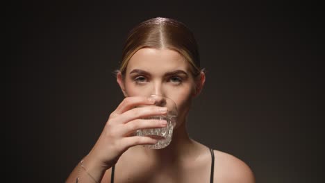Durstige-Frau-Trinkt-Wasser-Aus-Einem-Transparenten-Glas,-Schwarzer-Hintergrund