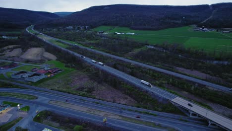Elevated-view-capturing-semi-trucks-driving-on-Interstate-80-surrounded-by-lush-greenery-and-hills-in-Pennsylvania