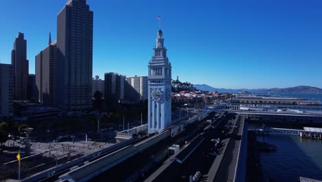 Aerial-orbit-around-San-Francisco-ferry-building-revealing-skyscrapers,-the-bay,-and-Alcatraz-in-the-background