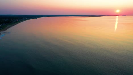 Aerial-Drone-View-of-Colorful-Ocean-Sunrise-in-Saco,-Maine-with-Bright-Colors-Reflecting-off-Calm-Rippling-Sea-Waves-Along-the-New-England-Atlantic-Coastline