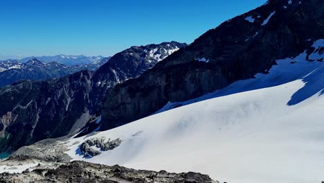Blick-Vom-Gipfel-Des-Joffre-Lakes-Provincial-Park-Unter-Der-Perspektive-Eines-Bergsteigers---Schwenk-Zeigt-Türkisfarbenes-Wasser-Von-Einem-Schneebedeckten-Alpenkamm-An-Einem-Sonnigen-Tag-Mit-Blauem-Himmel