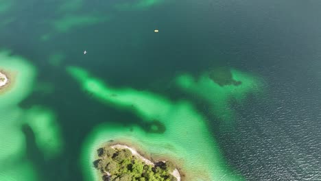 The-small,-lush-island-in-the-crystal-clear-waters-of-eibsee,-grainau,-germany,-aerial-view