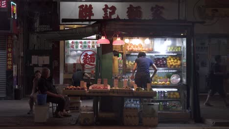 A-street-fruit-and-juice-stand-is-seen-open-late-at-night-in-Prince-Edward,-Kowloon,-Hong-Kong