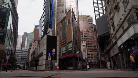 Blick-Auf-Die-Straße-Von-Hongkong-Mit-Vorbeifahrenden-Taxis-Und-Anderen-Autos-Und-Futuristischen-Hohen-Gebäuden-Im-Hintergrund