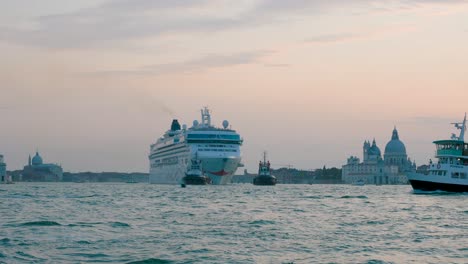 Large-cruise-ship-pulled-by-tugboats-on-busy-venetian-canal-towards-the-docking-lagoon