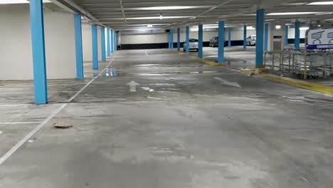 Moving-through-an-undercover-car-park-with-a-leaking-ceiling-and-very-few-vehicles-occupying-the-spaces