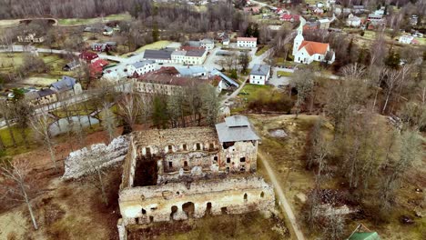 Aerial-panoramic-establishing-rotate-Ruana-castle-ruins,-Latvian-autumn-village