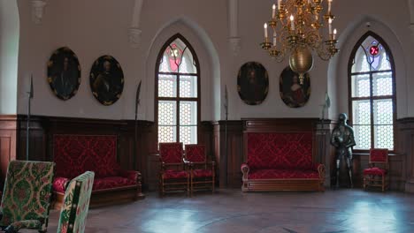 Opulento-Salón-De-Caballerías-En-El-Castillo-De-Trakoscan-Con-Muebles-Tapizados-En-Rojo,-Exhibición-De-Armaduras-Y-Retratos-Históricos