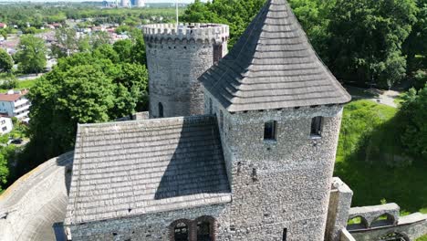 Medieval-Bedzin-castle-with-a-tower,-walls,-and-courtyard-during-a-beautiful-summer-day-surrounded-by-lush-greenery-under-a-clear-blue-sky
