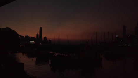 Langsamer-Schwenk-Sonnenuntergang-Zeitraffer,-Festgemachte-Boote-Auf-Dem-Wasser,-Skyline-Von-Hongkong