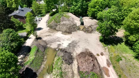 Sediment-stockpile-surrounded-by-bright-green-trees-with-still-water-mud-pools