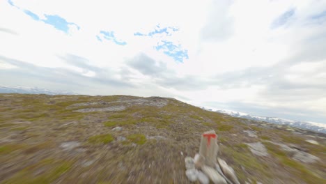 Aerial-flyover-mountaintop-of-Rossnos-and-male-person-standing-on-edge-of-cliff-wall,Norway