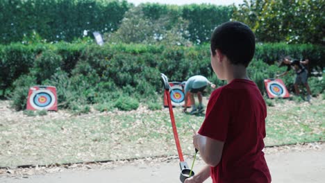 Zeitlupenaufnahme-Eines-Kleinen-Jungen,-Der-Einen-Plastikpfeil-Auf-Ein-Ziel-Abfeuert