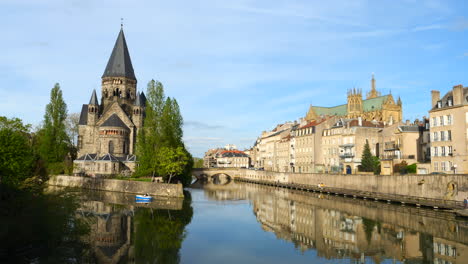 Tranquila-Escena-Fluvial-En-Metz,-Francia,-Con-Un-Pequeño-Barco-Histórico,-Arquitectura-Y-Un-Cielo-Despejado