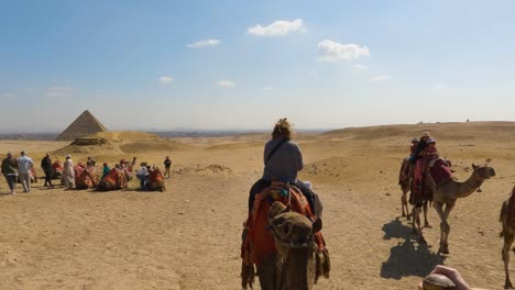 POV-of-person-riding-on-camel-across-open-desert-with-pyramid-in-distance
