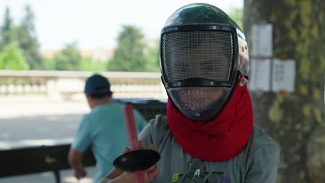 Toma-En-Cámara-Lenta-De-Un-Joven-Poniéndose-Un-Casco-De-Esgrima-Para-Protegerse