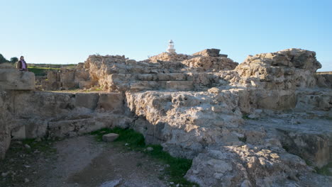 The-ruins-at-the-Archaeological-Site-of-Nea-Paphos,-with-a-lighthouse-in-the-background