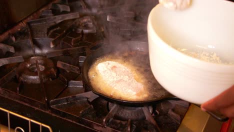 Cook-in-a-commercical-kitchen-careful-places-battered-chicken-breasts-into-hot-oil