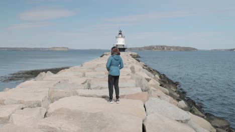 Mujer-Caminando-Hacia-El-Faro-Spring-Point-Cornisa-Al-Final-De-Un-Muelle-De-Roca-En-El-Océano-Atlántico