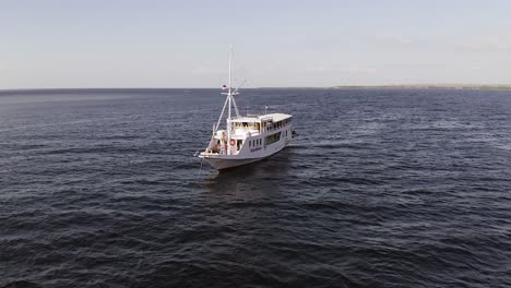 Barco-Turístico-Anclado-Junto-A-Pulau-Bedil,-Una-Pequeña-Y-Hermosa-Isla-Indonesia-Frente-Al-Escudo-De-Lombok,-Vista-Aérea