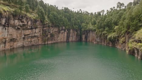 Aerial-drone-view-of-Tritriva-volcanic-lake-with-azure-water-and-cliffs-located-in-countryside-near-Antsirabe-in-Madagascar