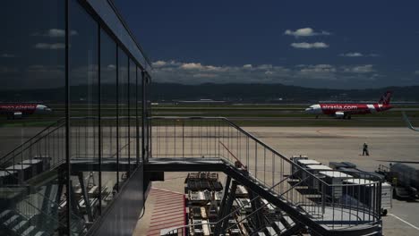 Air-Asia-airplane-on-the-runway-reflectinfg-in-the-glass-from-the-terminal