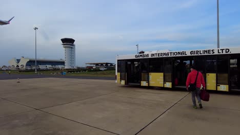 Pasajeros-Que-Desembarcan-Del-Avión-Sn-Brussels-En-La-Terminal-Del-Aeropuerto-Internacional-De-Banjul-Y-Abordan-El-Autobús-Del-Aeropuerto-Gia