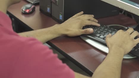 Primer-Plano-De-Las-Manos-De-Un-Joven-Estudiante-Escribiendo-En-Una-Computadora-Vieja-En-Una-Escuela-Pública-En-Honduras