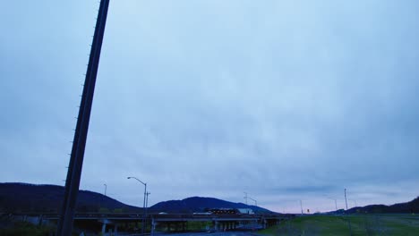 Overcast-sky-over-a-rural-highway-with-semi-trucks-traveling,-showcasing-the-trucking-industry's-role-in-logistics-and-transportation