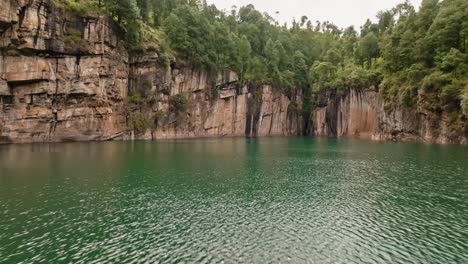 Fly-above-Tritriva-volcanic-lake-with-rock-cliffs-in-countryside-near-Antsirabe-in-Madagascar