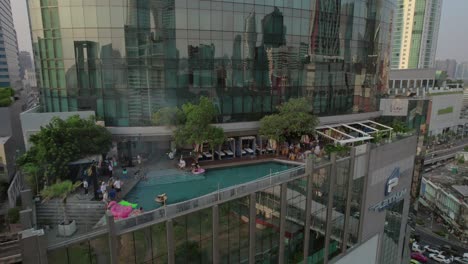 Städtische-Reflexion-Auf-Glasgebäude-Mit-Pool-Auf-Dem-Dach-In-Bangkok---Luftaufnahme
