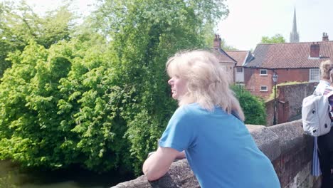 Blonde-haired-woman-looks-over-Bishops-stone-bridge-with-Norwich-cathedral-Spire-in-background