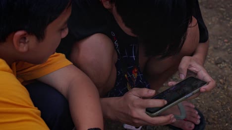 Two-Asian-boys-playing-video-games-online-on-smartphone-and-having-fun-together