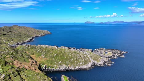 Drone-landscape-rocky-headland-calm-blue-sea-and-the-coastline-of-Ring-of-Kerry-in-the-background,Irelands-Wild-Atlantic-Way