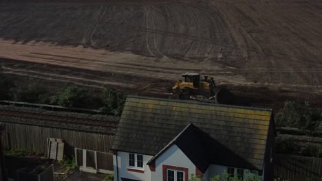 Luftaufnahme-Eines-Bulldozers,-Der-Im-Frühen-Morgensonnenaufgang-Schmutz-Hinter-Eine-Wohnbaustelle-Schiebt