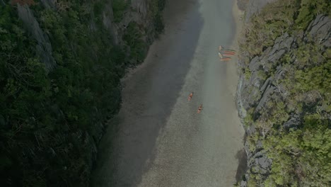 Aufsteigende-Luftaufnahmen-Von-Kanus-Im-Wasser-Neben-Buschigen-Klippen-Auf-Den-Sonnigen-Philippinen