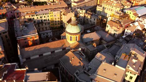 Genoa's-historic-center-at-sunset,-capturing-the-warm-glow-on-buildings-and-the-prominent-dome,-aerial-view
