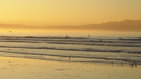 Gente-Surfeando-Durante-El-Amanecer-En-La-Playa-Dorada---Plano-Amplio