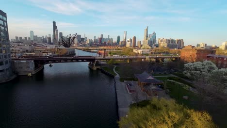 FPV-Drohnenansicht-Der-Goldenen-Stunde,-Ruhiger-Blick-Auf-Die-Skyline-Von-Chicago,-Wo-Sich-Die-Architektur-Neben-Einem-Ruhigen-Fluss-Erhebt-Und-Die-Harmonische-Mischung-Aus-Städtischem-Leben-Und-Natürlicher-Schönheit-Verkörpert