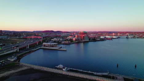 Twilight-aerial-shot-over-New-Haven,-CT,-highlighting-the-city's-roads-and-harbor-at-sunset