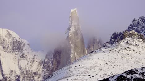 Zoom-out-establishing-shot-of-Cerro-Torre-covered-in-morning-mist-under-a-purple-lavender-light-in-Patagonia,-Argentina