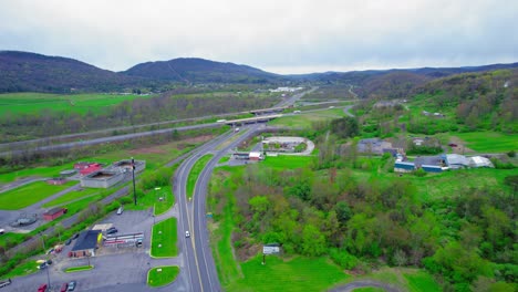 Drone-shot-of-a-highway-junction-with-semi-trucks-in-PA,-showing-the-interplay-of-transport-and-rural-commerce