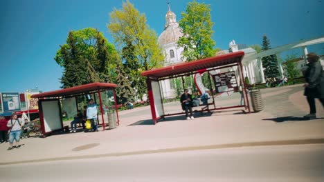 Pasando-Por-La-Parada-De-Autobús-Y-La-Iglesia-Católica-En-El-Centro-De-La-Ciudad-De-Daugavpils,-La-Capital-De-Latgola