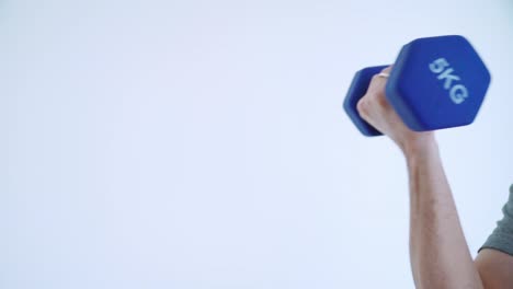 Arm-lifting-5kg-dumbbell-against-a-white-background-in-slow-motion