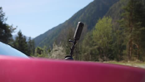 An-action-camera-or-cell-phone-is-mounted-on-the-hood-of-red-car-with-suction-mount