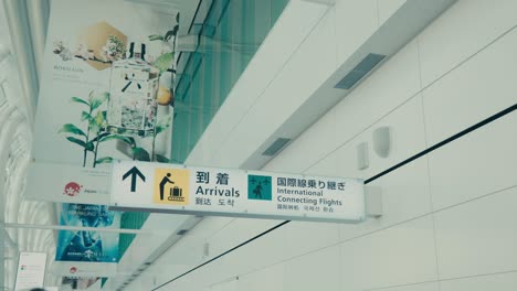 Señal-De-Llegadas-Para-Vuelos-Internacionales-De-Conexión-En-Un-Aeropuerto-De-Tokio,-Japón---Toma-De-ángulo-Bajo